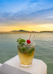 Mojito cocktail drink with evening sunset on beach background