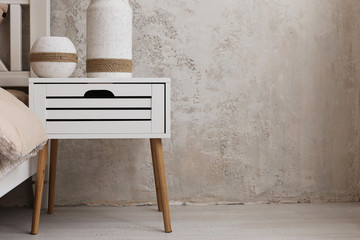 Bedside table, in a room with a handmade vase, in light colors.