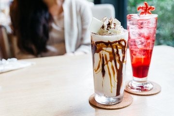 Caramel milkshake topping with whip cream and chocolate powder and strawberry Italian soda.