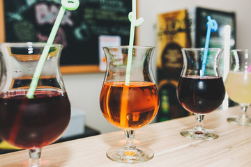 Colourful summer cocktails in glasses with straws. Drinks standing on the bar counter. Wine, pina colada and apple juice. Fresh and cold for summer weather.