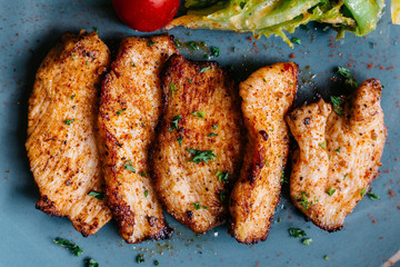Close up BBQ grilled chicken breast with salad served in blue plate on wooden table.