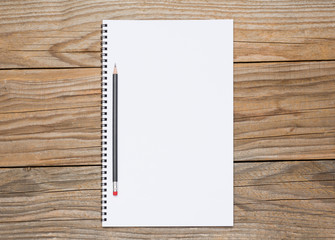 Blank page of a sketchbook with a black pencil over old wooden texture