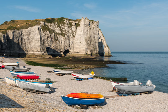 Boats in front of the halk cliffs of Etretat with the natural arch Porte d'Aval and the stone needle called L'Aiguille