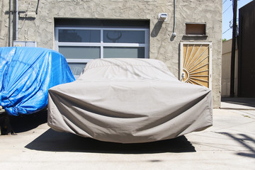 A view of two vintage cars with a cover in the street in Venice, California