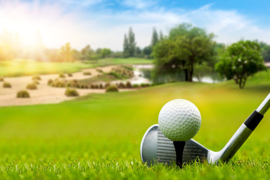 White Golf ball on tee ready to be shot on blurred beautiful landscape of golf course in bright day time with copy space. Sport, Recreation, Relax in holiday concept.	