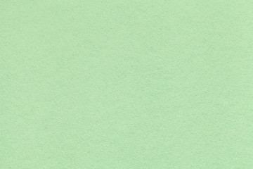 Texture of old light green paper closeup. Structure of a dense cardboard. The mint background.