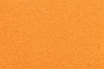 Texture of old bright orange paper background, closeup. Structure of dense carrot cardboard