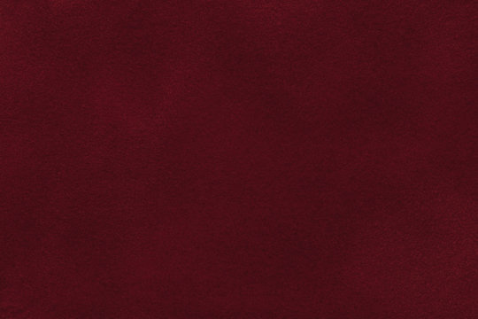 Background of dark red suede fabric closeup. Velvet matt texture of wine nubuck textile