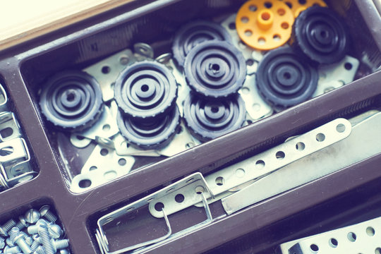 Metal parts and elements of the children's building kit lying in the box.