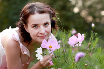 Fine emotional brunette with flower from flowerbed, close up portrait. Yonge girl in vintage pink pastel with live expressions on beautiful country and old background.