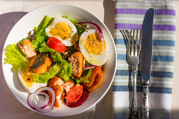 Healthy diet salad with salmon, tomatoes, eggs, onion and lettuce, top view. Dietary lunch