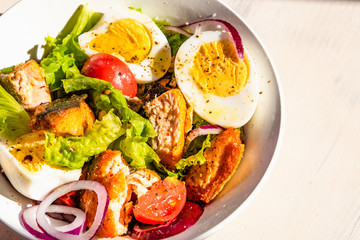 Paleo diet salad with salmon, tomatoes, eggs, onions and lettuce, top view, copy space