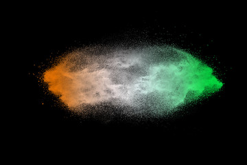 Green orange dust particles explosion on black background. Color powder dust splash.