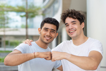 Portrait of happy multiethnic male friends making fist bump. Young Indian and Hispanic male...