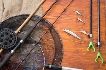 Fishing tackle-fishing spinning rods, hooks, floats and lures on wooden background