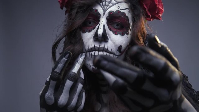 Beautiful woman beckons to herself, makeup skull for halloween