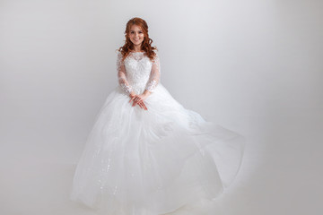 Fototapeta na wymiar Lovely young woman bride in a lavish wedding dress. Light background.