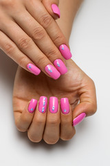 Fototapeta premium summer pink manicure with triangles, crystals, silver on short square nails on a white background