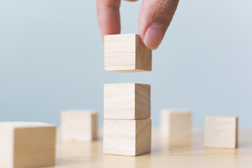 Hand arranging wood block stacking on top with wooden table. Business concept for growth success...