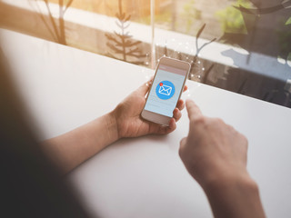 Woman hand holding mobile phone with e-mail icon. Email marketing or contact us concept.