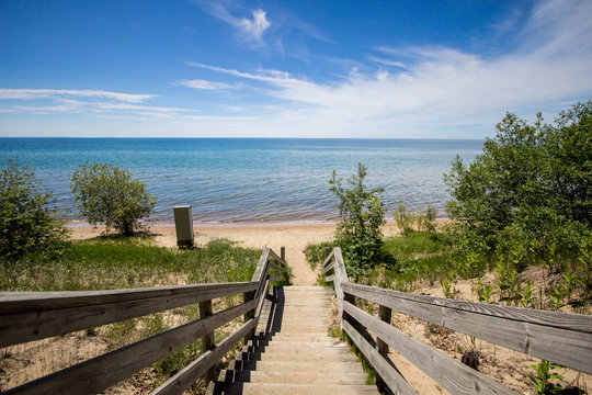 Stairs To The Beach. Wooden staircase leads to a scenic wide sandy beach on a sunny summer day on the Great Lakes coast. 
