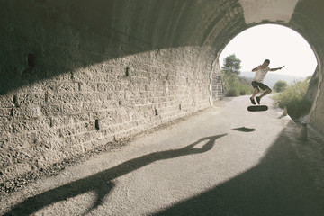 Young man in tunnel with skateboard posing in wide angle image