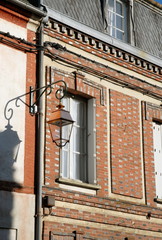 Fototapeta na wymiar Ville de Rugles, façade typique normande en briques rouges, lanterne et fenêtre, département de l'Eure, Normandie, France