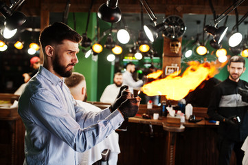 Handsome bearded man at the barbershop, barber at work with fire show.