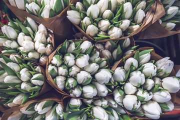 White tulip bouquets in paper bags