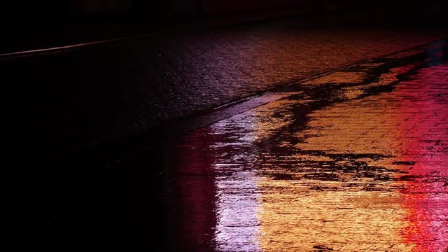 Raindrops are falling in the puddle with neon lights