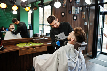 Handsome bearded man at the barbershop, barber at work.