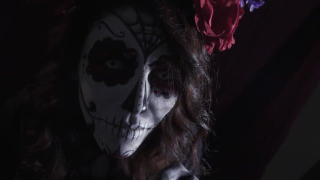 Top view of a girl with a makeup skull and a wreath of roses on her head
