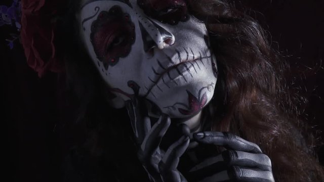 Beautiful girl in makeup Santa Muerta on halloween posing in the dark