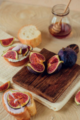 Autumn dessert: sweet toast with ripe figs, soft cheese and honey on a light background.