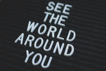 Phrase see the world around you written on the letter board. White letters on the black background. Business concept