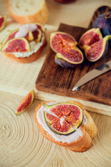 Autumn dessert: bruschetta with ripe figs, soft cheese and honey on a light background.