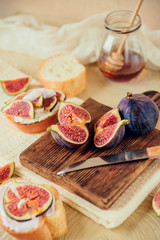 Autumn dessert: bruschetta with ripe figs, soft cheese and honey on a light background.