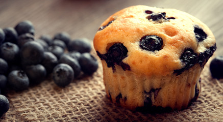 muffin with blueberries on a wooden table. fresh berries and sweet pastries on the board.