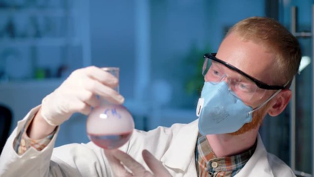 Scientist in mask holding a flask with methyl