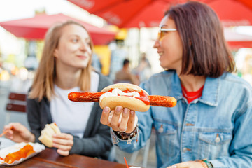 Woman eating Currywurst fast food German sausage in outdoor street food cafe