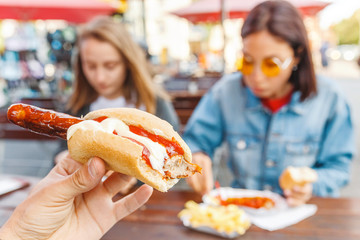 Woman eating Currywurst fast food German sausage in outdoor street food cafe © EdNurg