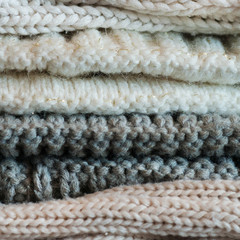A stack of textured knitted things of light colors. The concept of comfort, warmth.