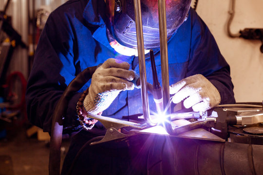Professional car mechanic working in auto repair service on argon gas cutting machine