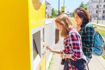 young woman paying at ticket machine in a public transport station