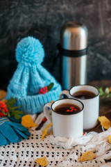 Autumn walk concept: hat, gloves, thermos, hot tea and autumn leaves