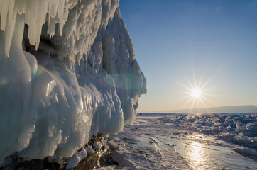 Lake Baikal is covered with ice and snow, strong cold, thick clear blue ice. Icicles hang from the...