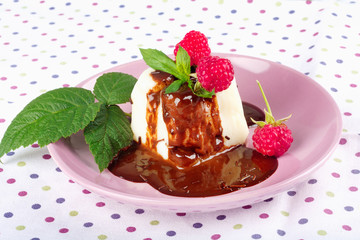 Cream pudding with chocolate sauce, raspberry and mint on  tablecloth