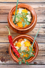 Traditional rustic home  gulyas, with raw vegetables and spices in clay pots on  wooden table.