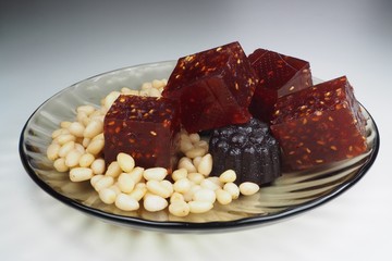 pieces of natural marmalade and pine nuts in a glass plate