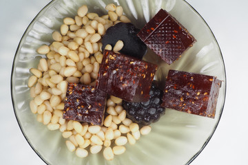 pieces of natural marmalade and pine nuts in a glass plate